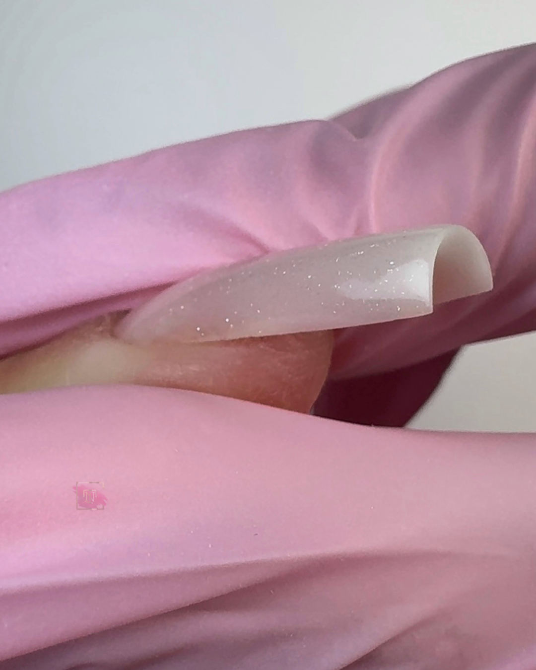 Soft pink glitter gel nails close-up showing smooth apex and elegant nail extension structure